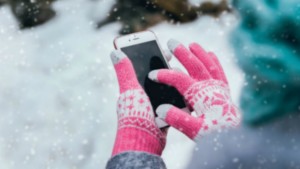 Woman using smartphone in winter with gloves for touch screens. Backgound